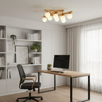A Clérachic flush-mount light with warm frosted globes over a home office, with white shelving, a black-framed desk and a mesh chair.