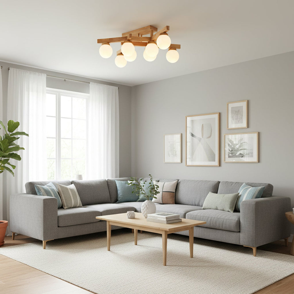 Wood-frame Clérachic ceiling light seen from across a bright living room with a grey corner sofa, a pale rug and tall windows with sheer curtains.