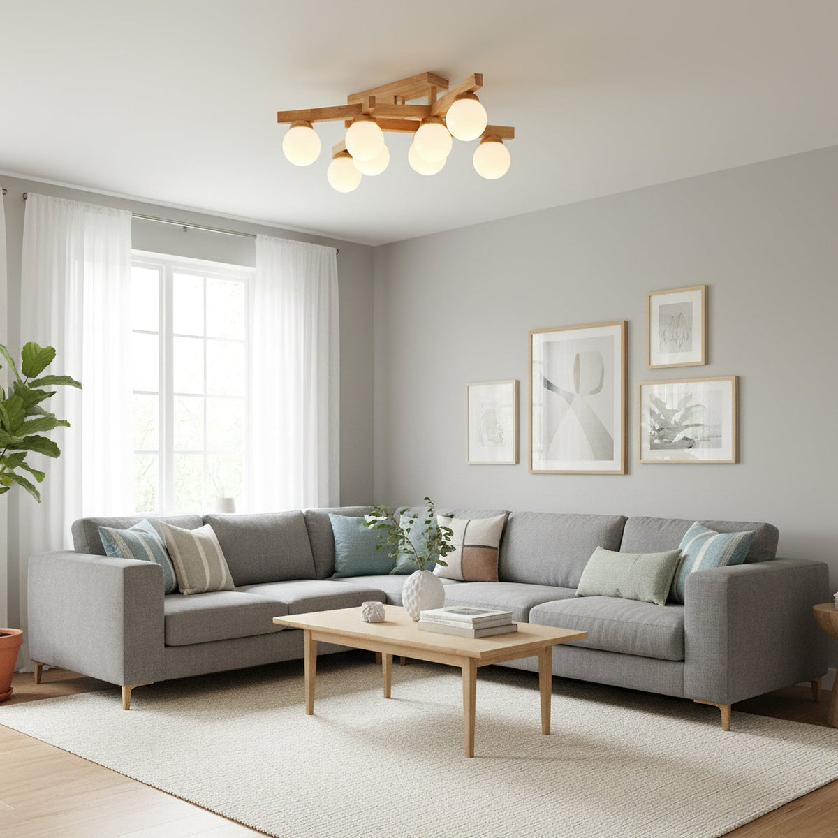 Wood-frame Clérachic ceiling light seen from across a bright living room with a grey corner sofa, a pale rug and tall windows with sheer curtains.