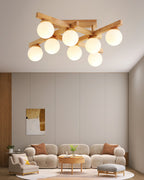 This Clérachic eight-globe ceiling light hangs above a living room with a curved beige sofa, a round wood table and a tall abstract artwork.