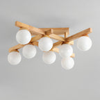 Eight white globes, unlit, on the crossed wood arms of this Clérachic ceiling light, photographed against a pale grey ceiling.