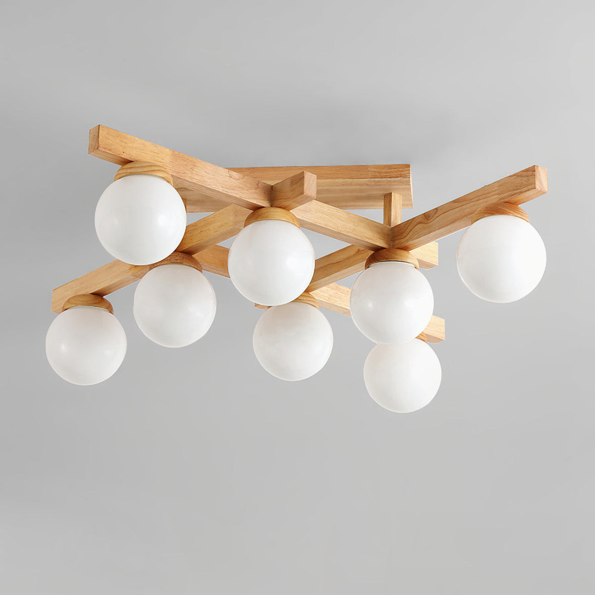 Eight white globes, unlit, on the crossed wood arms of this Clérachic ceiling light, photographed against a pale grey ceiling.