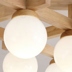 Close view of a large frosted globe seated in its wood cap on the crossed wood arms of this Clérachic ceiling light.