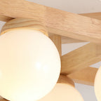 Close view of the wood grain on the arm and the rounded wood cap holding a frosted white globe on this Clérachic ceiling light.