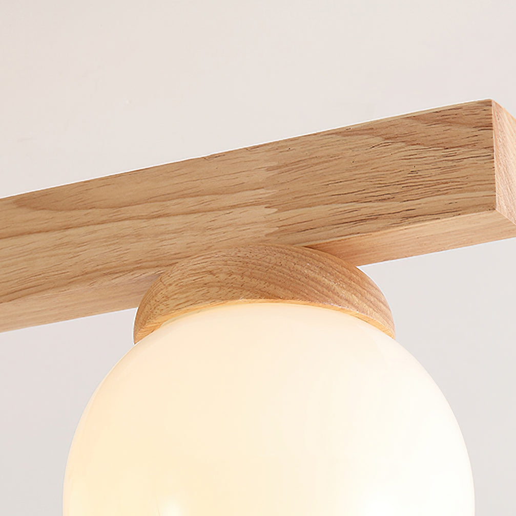 Close view of a single flat wood arm and the turned wood collar around a lit frosted globe on this Clérachic ceiling light.