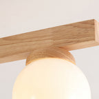 Close view of a single flat wood arm and the turned wood collar around a lit frosted globe on this Clérachic ceiling light.