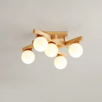 Five lit frosted globes on a compact wood cross frame, this Clérachic ceiling light seen from below against a pale grey ceiling.
