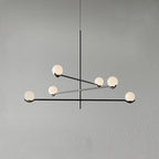 A black Clérachic chandelier with six frosted globes, its arms crossing at different heights, on a plain grey wall.