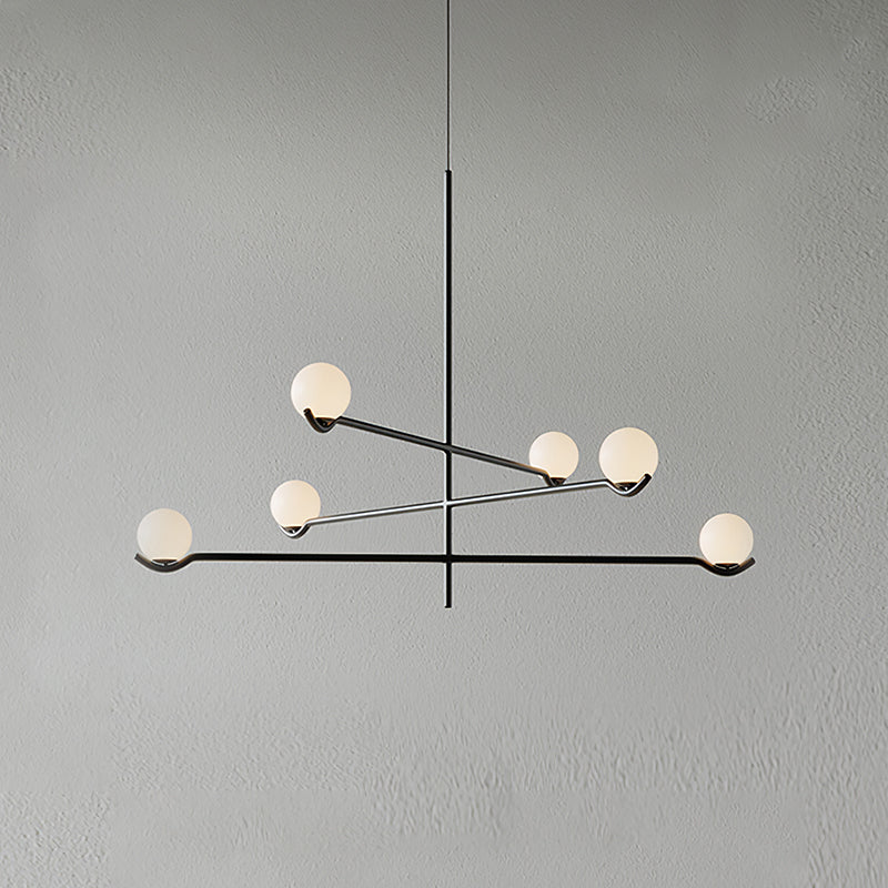 A black Clérachic chandelier with six frosted globes, its arms crossing at different heights, on a plain grey wall.
