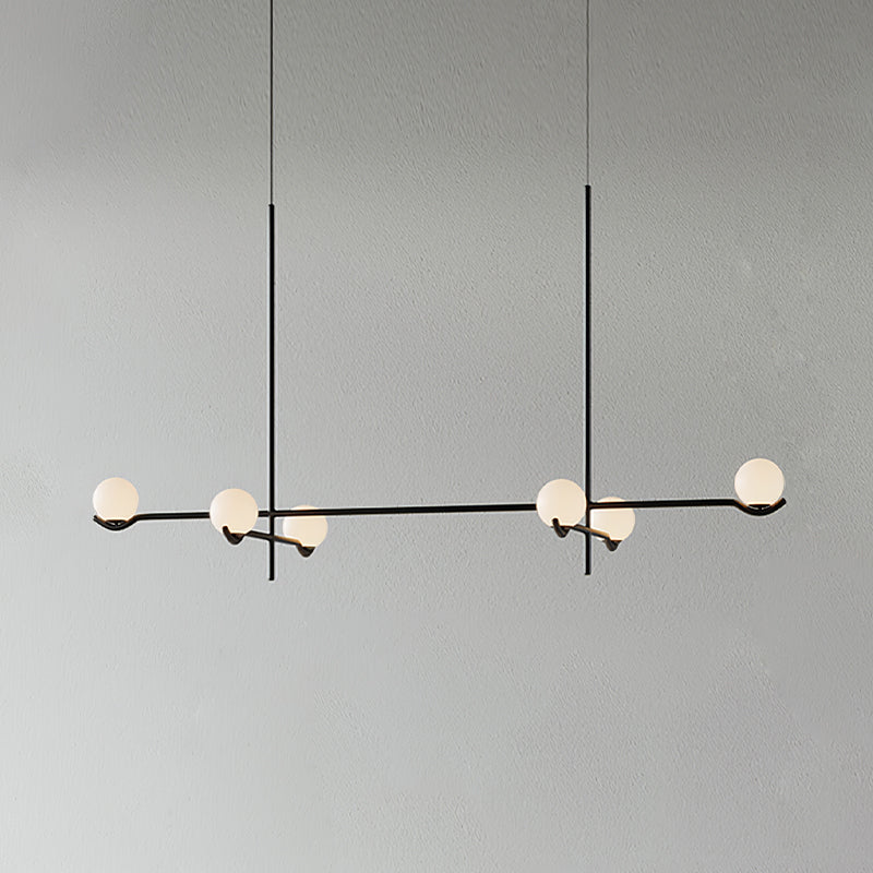 A long Clérachic chandelier in black on two rods, with six frosted globes along its arms, on a plain grey wall.