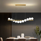 A gold Clérachic Frosted Globe Linear Pendant Light spans a dining room ceiling framed by wood slat paneling and crown molding.