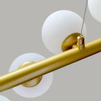 A close-up of two frosted globes and a suspension cable on the Clérachic Frosted Globe Linear Pendant Light.