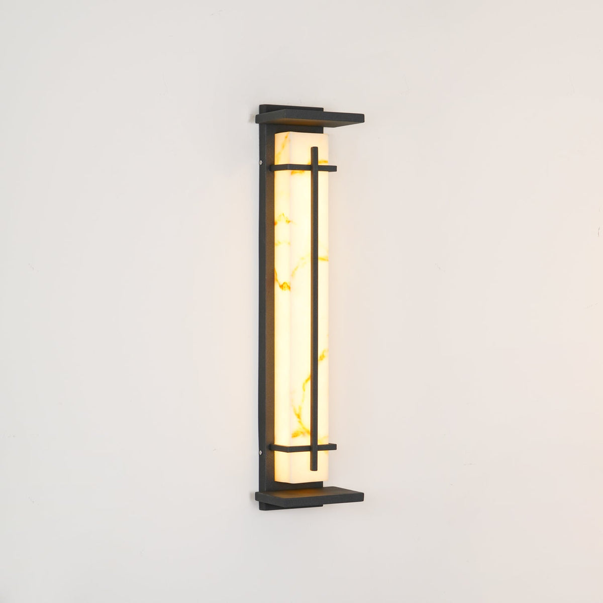 Unlit wall light on a cream wall, its pale resin shade showing soft golden veining inside a dark frame; from Clérachic.