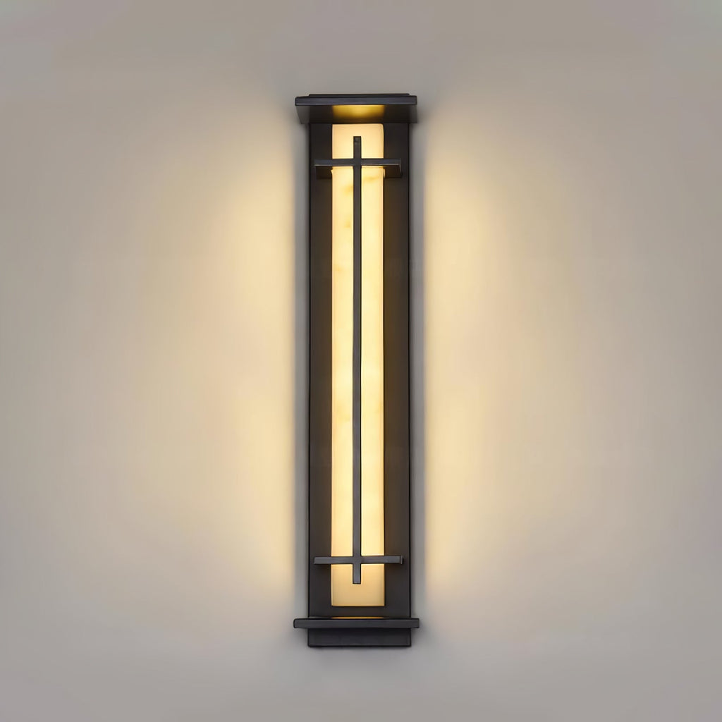 Long, slim Clérachic wall light lit warm on a stone-coloured wall, the light spreading evenly either side of the frame.