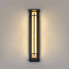 Long, slim Clérachic wall light lit warm on a stone-coloured wall, the light spreading evenly either side of the frame.
