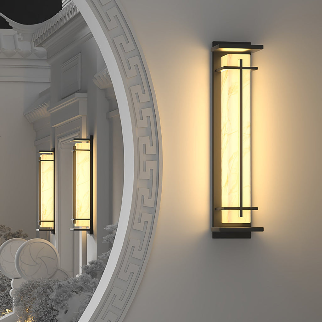 Clérachic wall light lit on a white wall beside a curved ornamental opening, two smaller lights glowing in the arch beyond.
