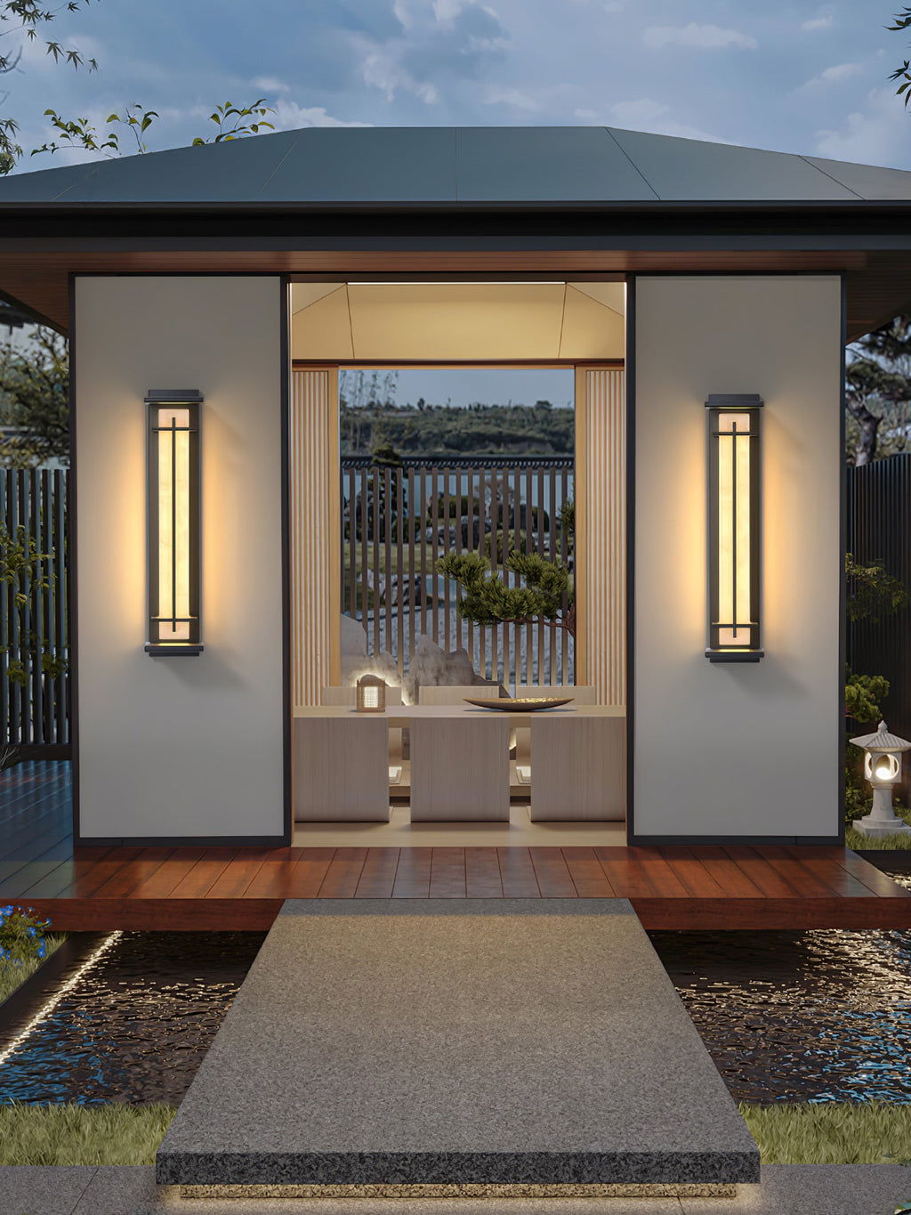 Two lit Clérachic wall lights either side of a pavilion doorway, with a timber deck and a stone path across water.