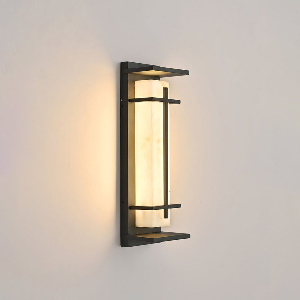 This Clérachic wall light glows softly on a warm beige wall, the dark frame and the pale shade seen at a slight angle.