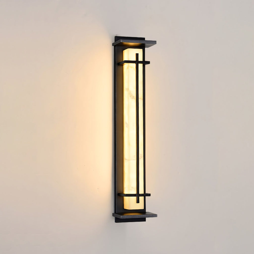 Dark-framed Clérachic wall light lit warm on a cream wall, its pale shade bright with soft shadowing at the top.