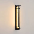 Dark-framed Clérachic wall light lit warm on a cream wall, its pale shade bright with soft shadowing at the top.