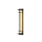 Lit Clérachic wall light on white, with the warm shade visible and a thin glow at the top of the dark frame.