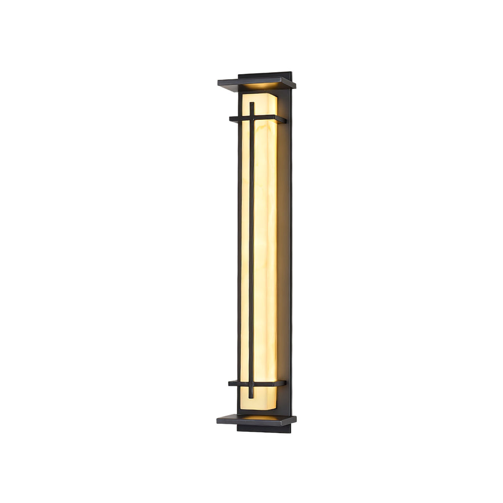 Taller lit Clérachic wall light on a white backdrop, with the glowing shade seen from a slight angle between its dark bars.