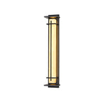Taller lit Clérachic wall light on a white backdrop, with the glowing shade seen from a slight angle between its dark bars.