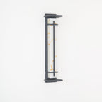 Close view of the unlit wall light, golden marks in its white shade and a grey metal frame, on a white wall; from Clérachic.