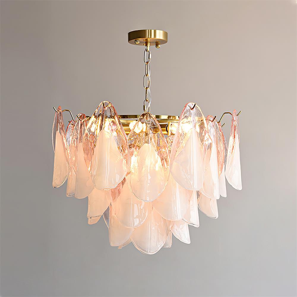 Clérachic chandelier with blush pink glass petals hangs lit from a brass chain against a plain wall.