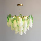 Clérachic chandelier in sage green petals photographed from a slight side angle, bulbs glowing warm.