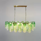 The Clérachic chandelier in sage green glass petals hangs on a brass chain, photographed head-on.
