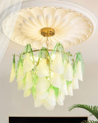 Clérachic chandelier in sage green glass petals hangs near a sheer curtain, ceiling medallion above.