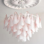 The Clérachic chandelier in blush pink glass petals lit beneath a white ceiling medallion.