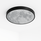 Clérachic round black-rimmed ceiling light with a moon-surface print on its diffuser, shown unlit against a white ceiling.