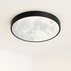 Clérachic slim black-framed flush ceiling light, glowing softly white with a full-moon crater pattern across the disc.