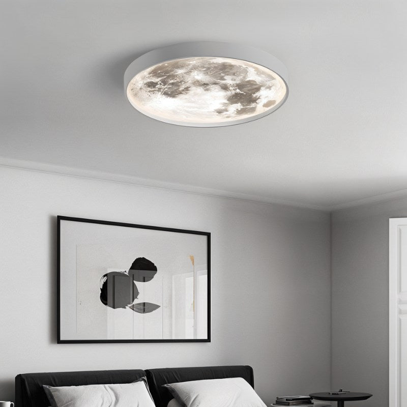 Clérachic white-rimmed moon ceiling light lit above a bedroom with a black headboard and a framed abstract print.