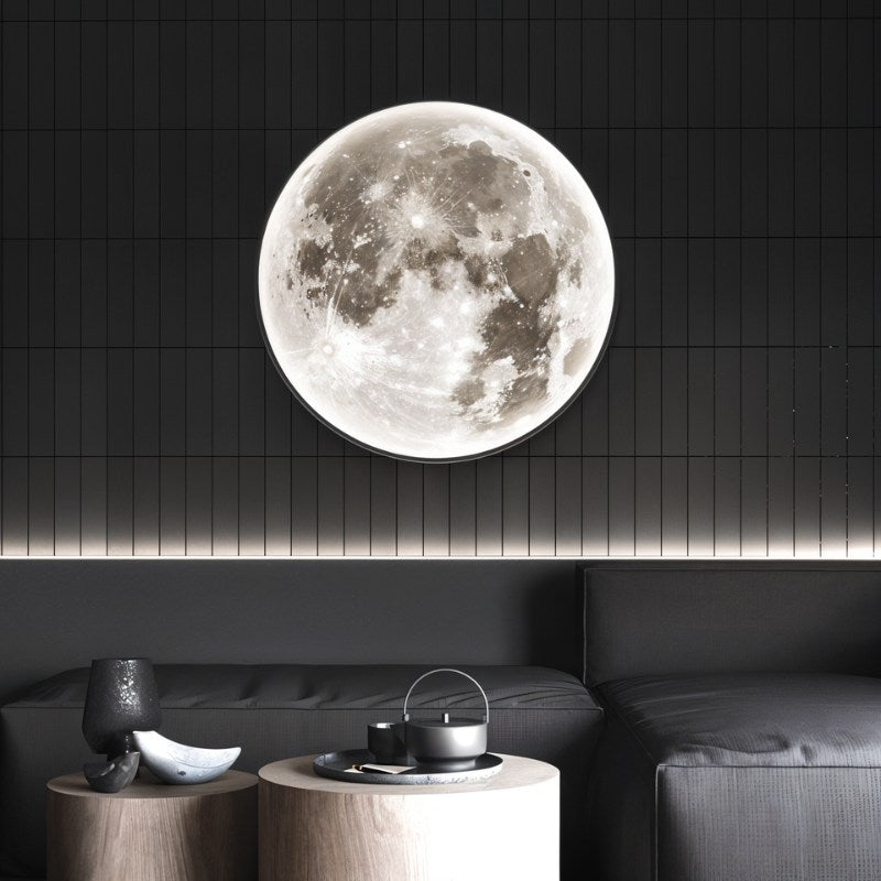 Clérachic large moon-face disc light with a black edge, mounted on a dark tiled wall above a charcoal sofa and wooden tables.