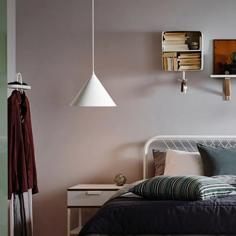 A white Clérachic Funnel Pendant Light hung low beside a bed, lighting the bedside table rather than the whole bedroom.