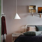 A white Clérachic Funnel Pendant Light hung low beside a bed, lighting the bedside table rather than the whole bedroom.