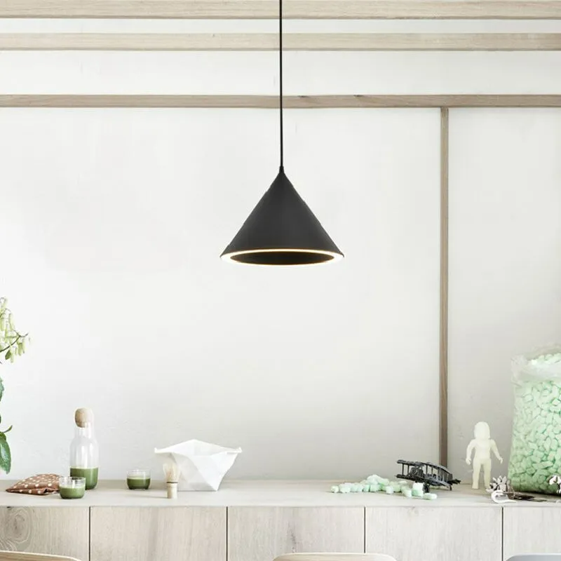 A black Clérachic Funnel Pendant Light over a pale oak sideboard, its lit rim picking out the objects arranged below.