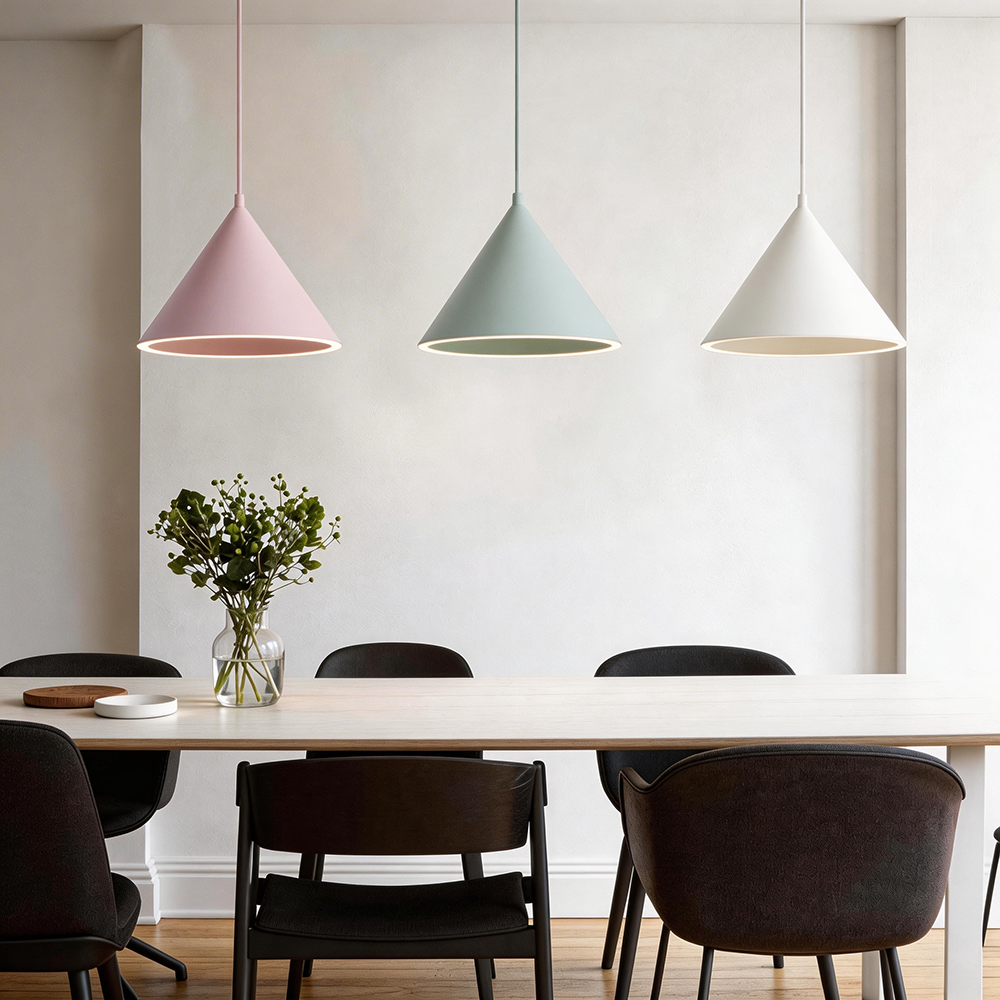 Pink, gray and white Clérachic Funnel Pendant Lights hung in a line over a long dining table set with black chairs.