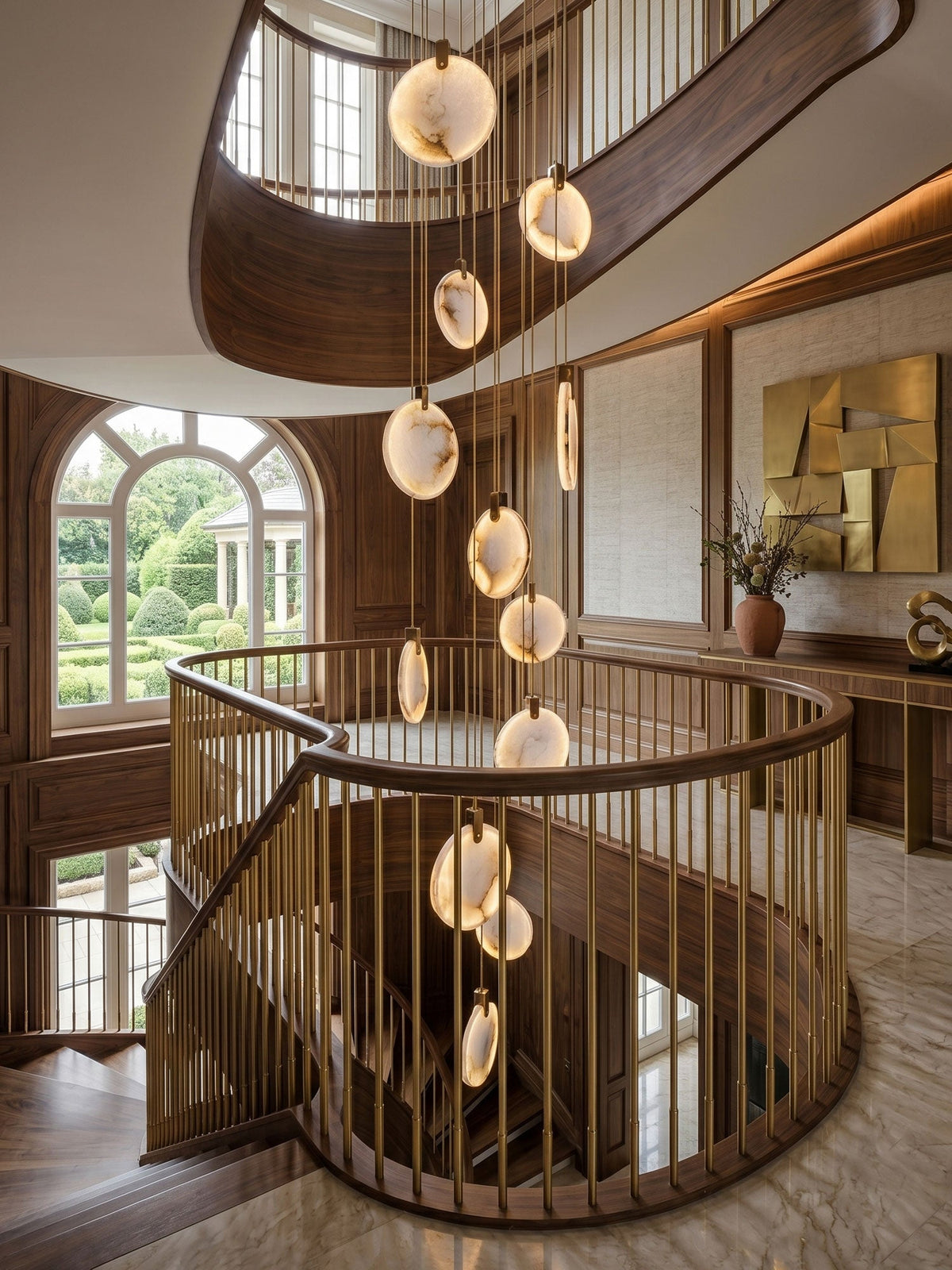 Alabaster disc pendants of this Clérachic cluster hang down a spiral staircase with a brass balustrade, beside an arched window.