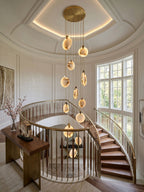 Looking across a round entrance hall, a Clérachic alabaster disc cluster hangs from a gold canopy beneath a lit ceiling recess.