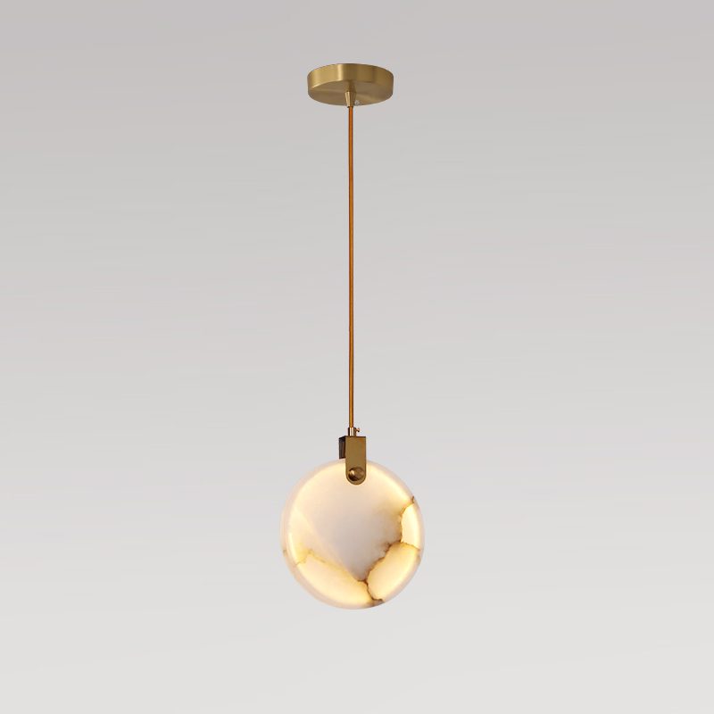 Clérachic alabaster disc pendant on a long brass rod with a gold ceiling plate, lit warm and shown on a grey backdrop.