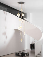 A closer view of the lit Clérachic disc cluster beside a curving white staircase, with a black sideboard in the distance.