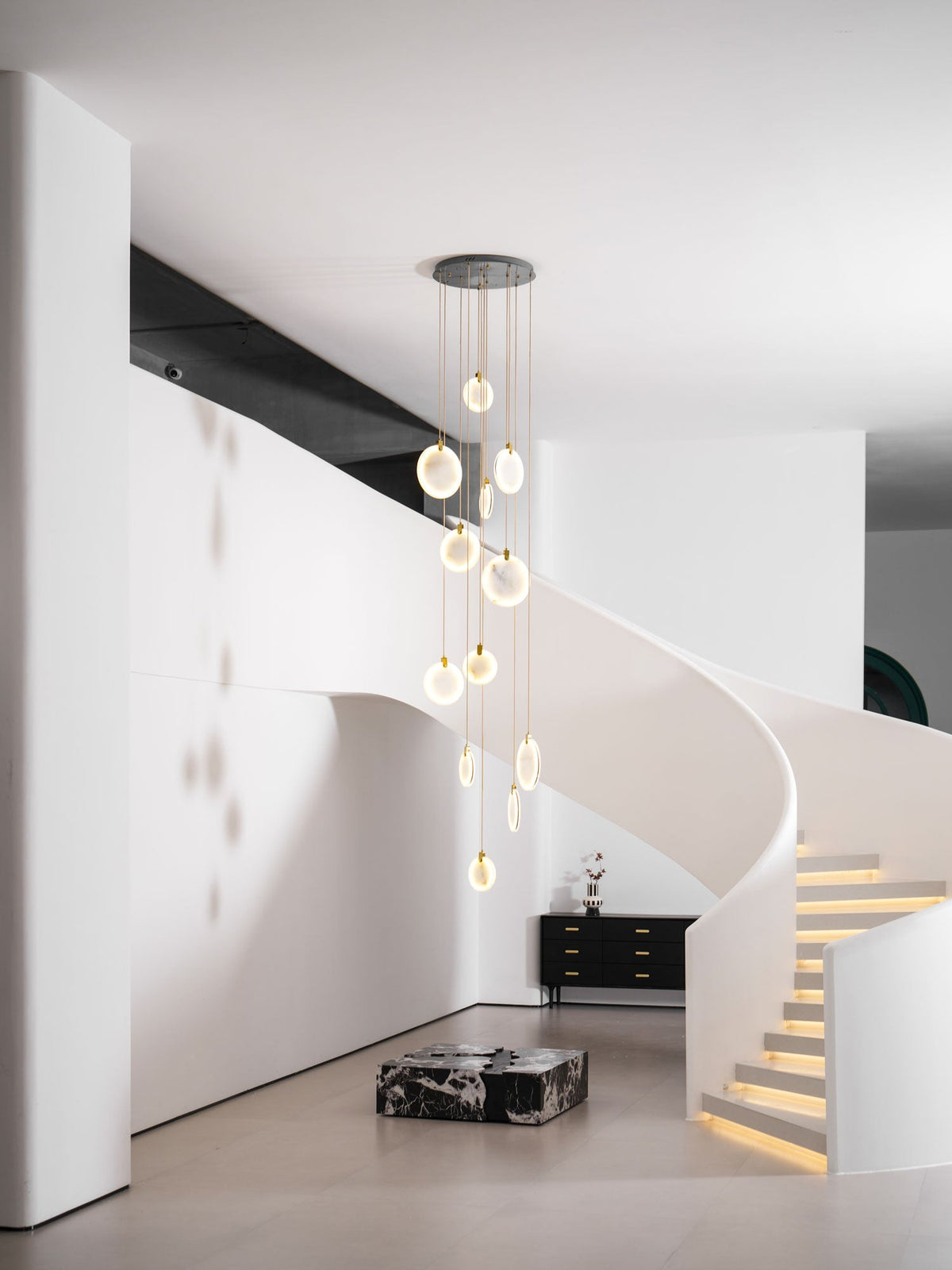 A high view of the Clérachic cluster with lit alabaster discs, in a white hall with a curved stair and glowing steps.