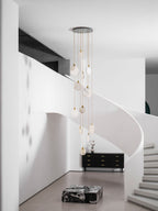 Unlit Clérachic alabaster discs, pale and milky, hang from a dark ceiling plate in a white hall with a curving stair.