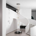 Clérachic alabaster disc pendants hang unlit beside a white curved wall, with a black sideboard and stone-coloured steps.