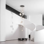 A Clérachic alabaster disc cluster seen unlit from a distance, in a hall with a white curved stair and a dark marble plinth.