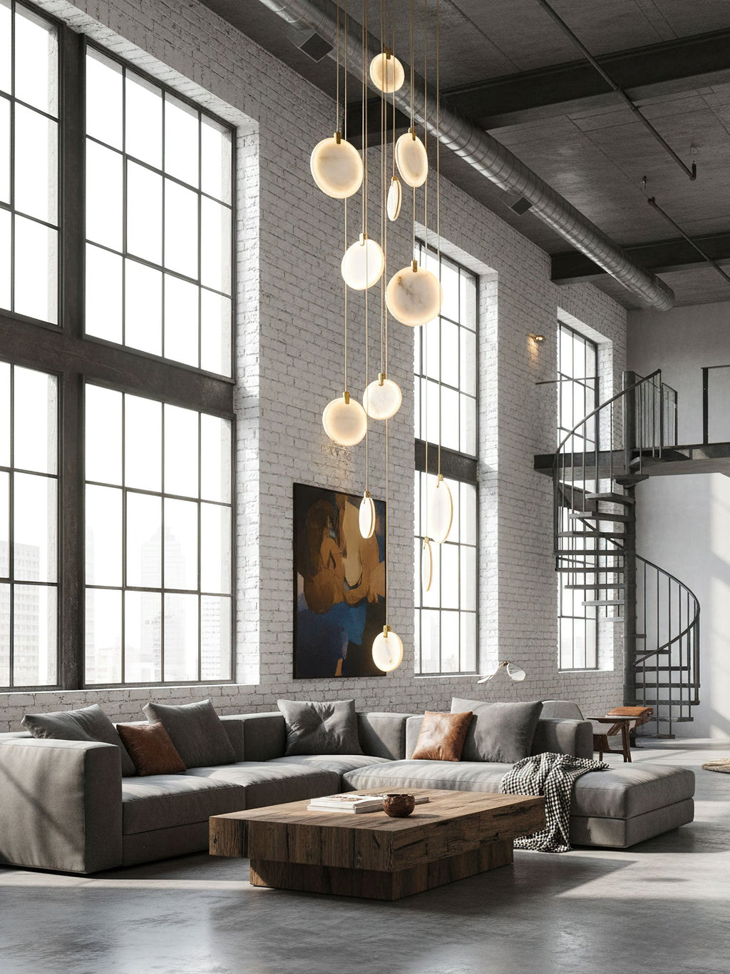 Clérachic alabaster disc pendants hang in a white-brick loft with tall black-framed windows, a grey corner sofa and a spiral stair.